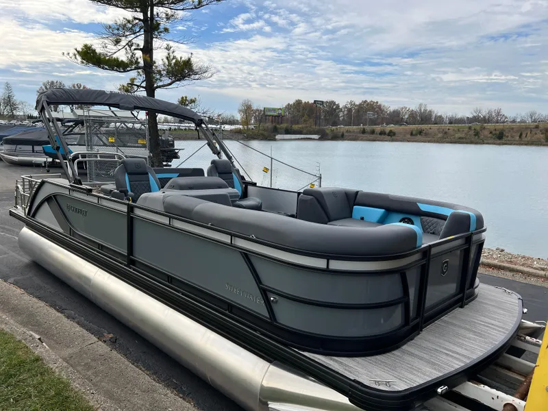Slide: The Image of 2025 Godfrey Sweetwater 2286 sFLC TRI PWR STR pontoon boat docked by a serene lake. - 3