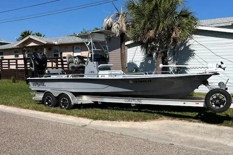 Slide: The Image of 2019 Haynie 25 Magnum boat on trailer, parked near palm trees and houses. - 11