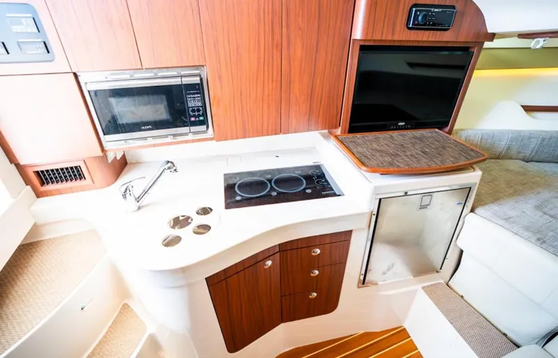 Slide: The Image of 2021 Grady-White Express 330 interior with kitchenette, featuring stove, microwave, and seating area. - 18