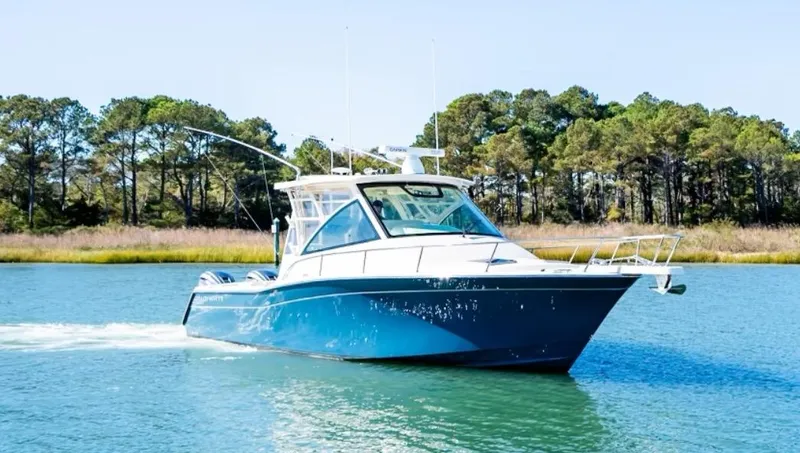 Slide: The Image of 2021 Grady-White Express 330 boat cruising on a serene lake with forested background. - 4