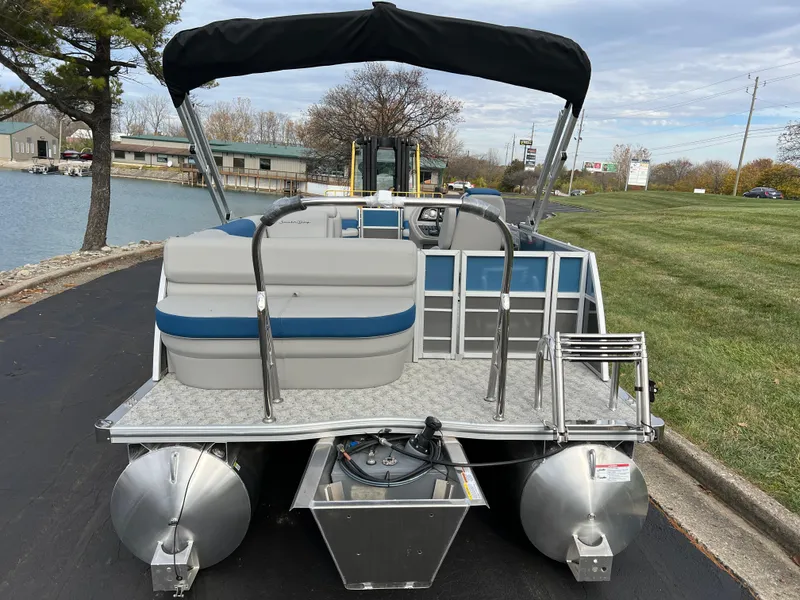 Slide: The Image of 2025 South Bay 222 CR2 LE pontoon boat with canopy, docked by a lakeside. - 5