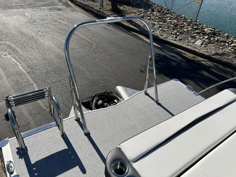 Slide: The Image of 2025 South Bay S 224 UL pontoon boat deck with ladder and railing by the water. - 14
