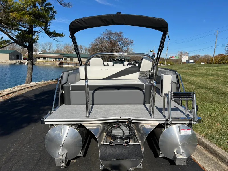 Slide: The Image of 2025 South Bay S 224 UL pontoon boat, rear view, docked by a scenic lakeside. - 5