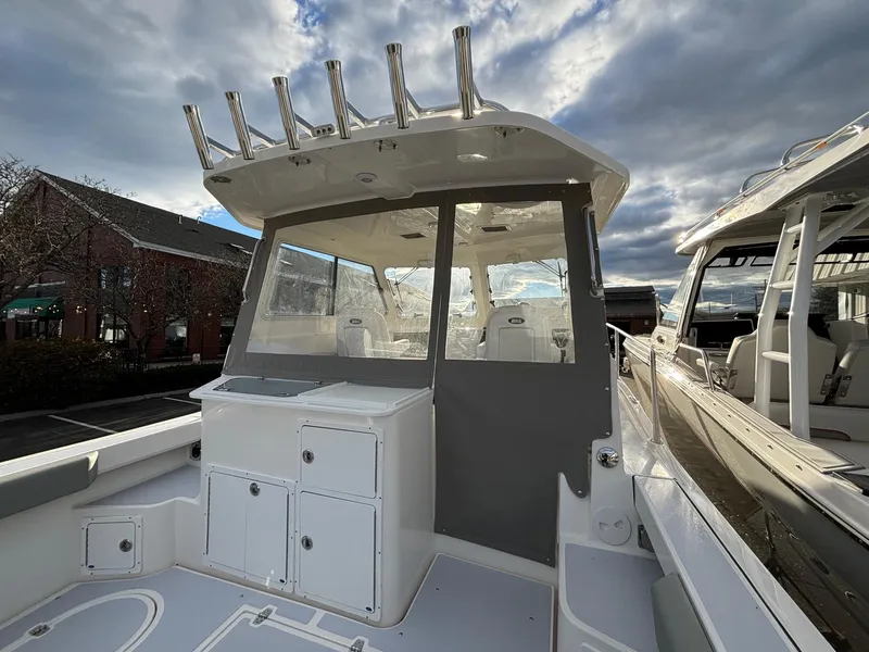 Slide: The Image of 2025 NorthCoast 285 Cabin boat with spacious deck and rod holders under cloudy sky. - 10
