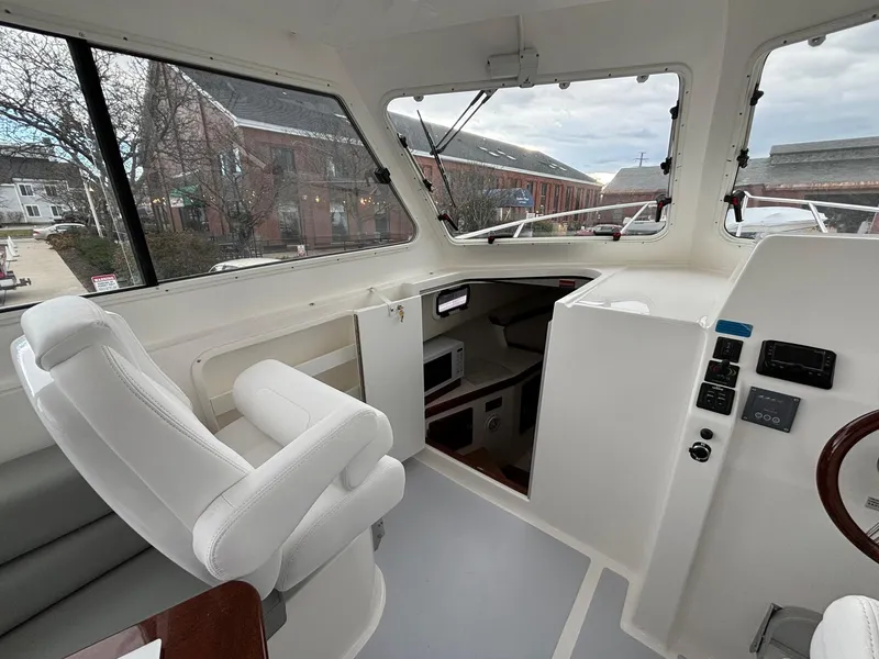 Slide: The Image of Interior of 2025 NorthCoast 285 Cabin boat with white seating and control panel. - 13