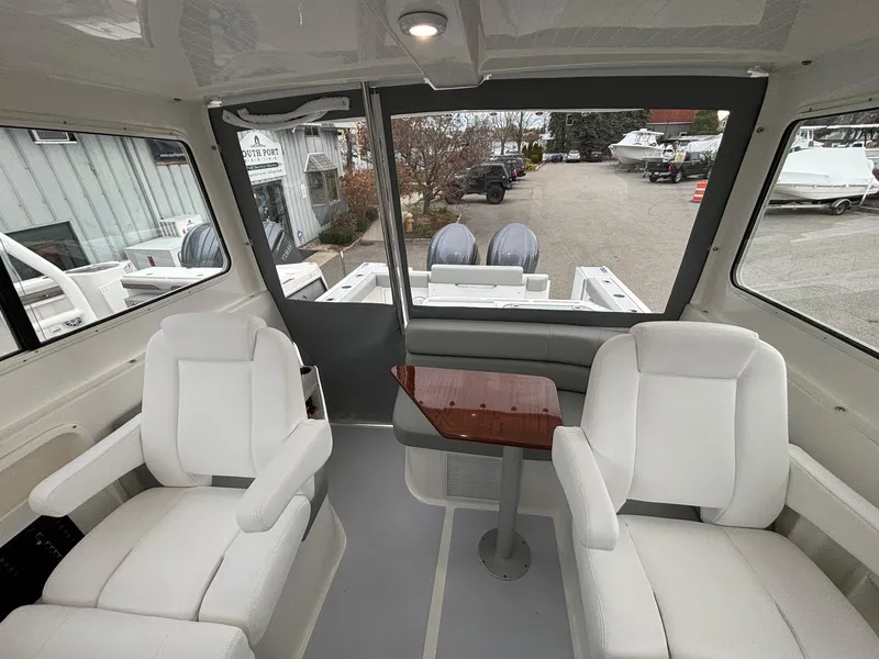 Slide: The Image of Interior of 2025 NorthCoast 285 Cabin boat with white seating and table. - 15