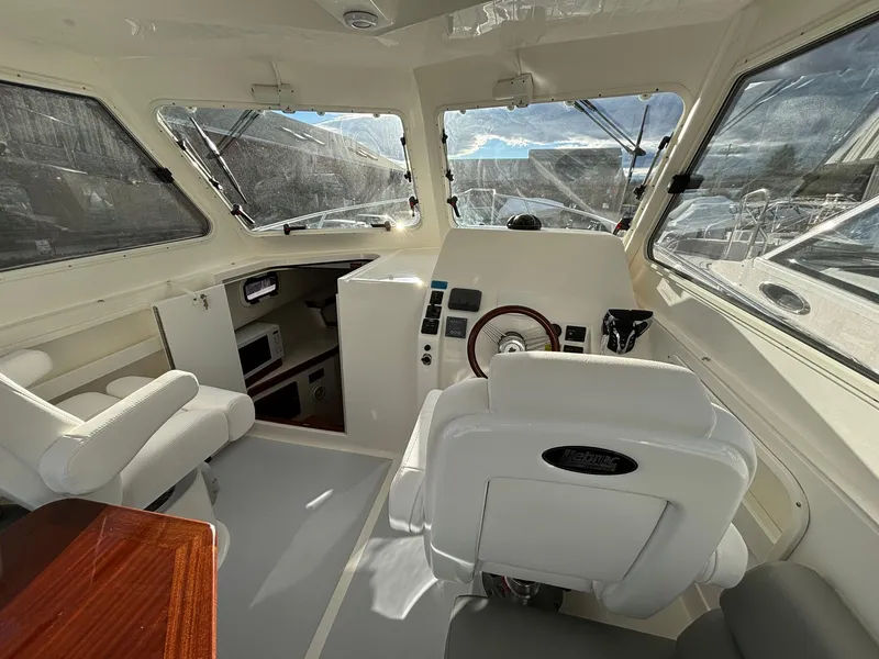 Slide: The Image of 2025 NorthCoast 285 Cabin interior with helm, seating, and panoramic windows. - 17