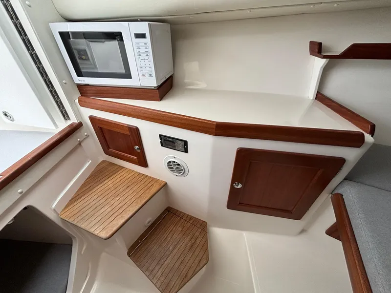 Slide: The Image of 2025 NorthCoast 285 Cabin interior with microwave, wooden cabinets, and steps. - 22