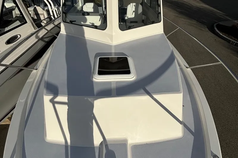 Slide: The Image of 2025 NorthCoast 285 Cabin boat deck with hatch, docked in sunlight. - 6