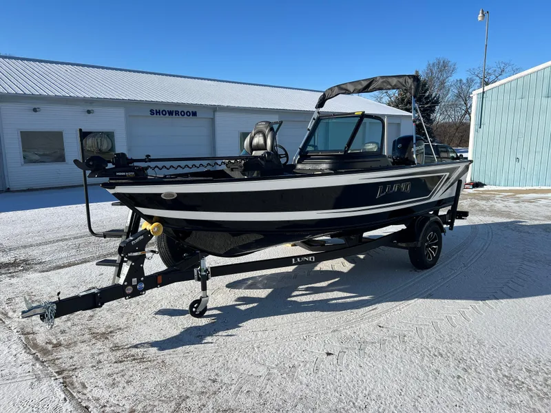 Slide: The Image of 2025 Lund 1775 Impact XS Sport boat on trailer in snowy showroom lot. - 2
