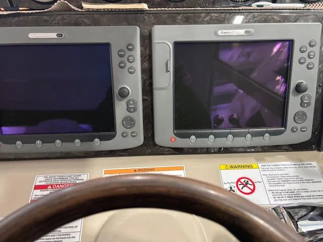 Slide: The Image of Dashboard of a 2009 Sea Ray 48 Sundancer with navigation screens and warning labels. - 21