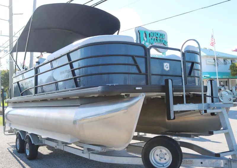 Slide: The Image of 2021 Sweetwater 2186 MT pontoon boat on trailer, black canopy, outdoor display. - 2