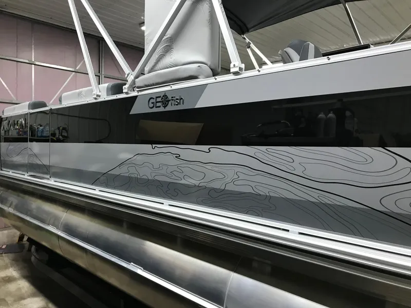 Slide: The Image of 2025 Avalon GEOfish REAR FISH boat with sleek design and contour graphics in a showroom. - 2