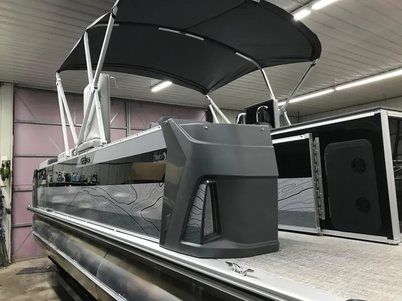 Slide: The Image of 2025 Avalon GEOfish REAR FISH boat in a showroom, featuring sleek design and canopy. - 3