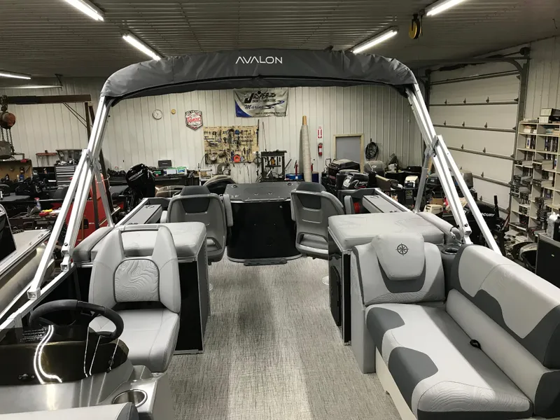 Slide: The Image of 2025 Avalon GEOfish REAR FISH boat interior with gray seating and canopy in a workshop. - 32