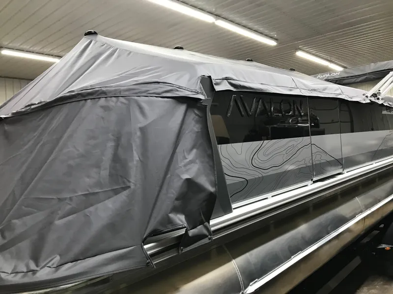 Slide: The Image of 2025 Avalon GEOfish REAR FISH boat with protective cover in a garage setting. - 47