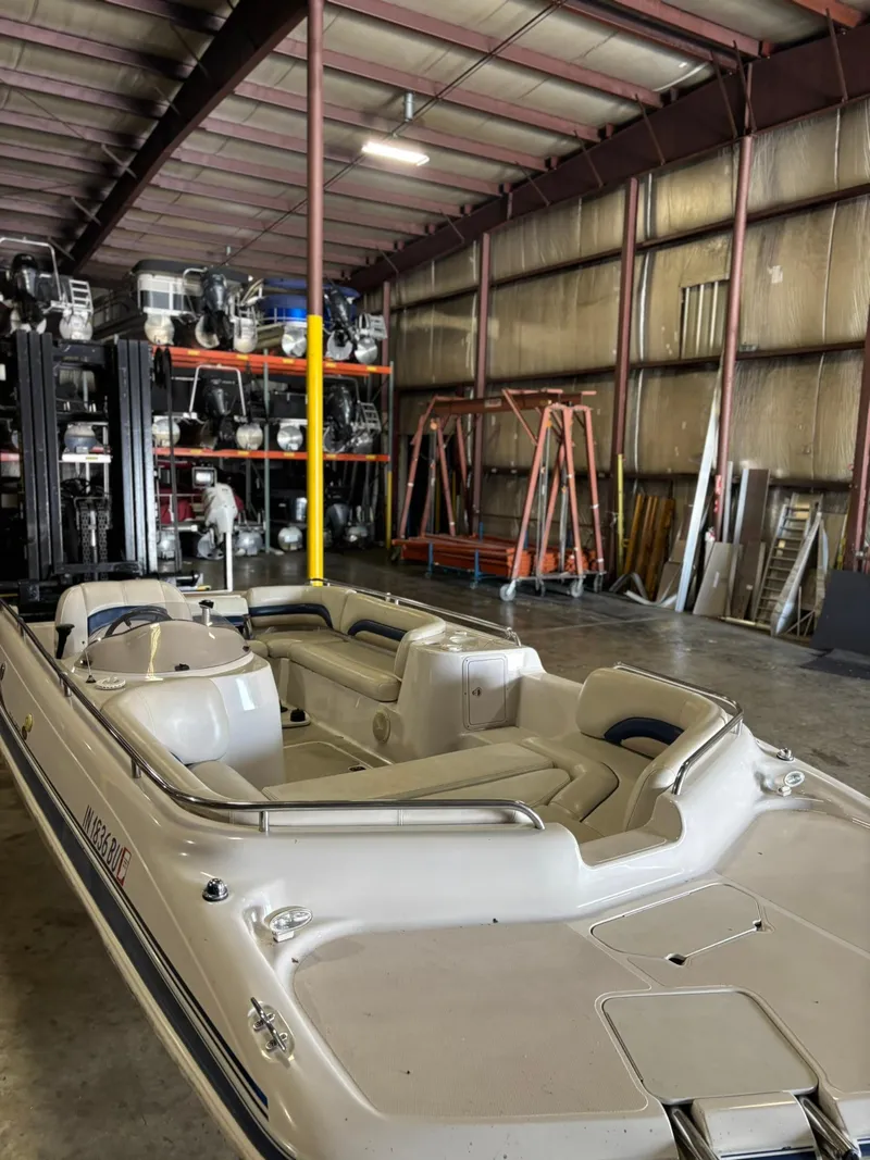 Slide: The Image of 2001 Hurricane FunDeck GS 201 I/O boat in storage warehouse, surrounded by equipment. - 12