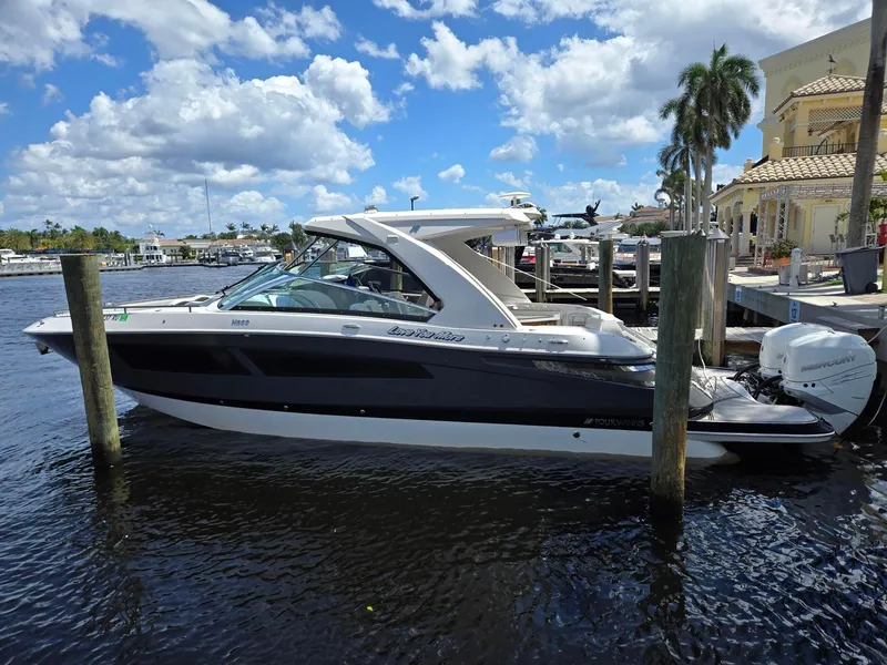 Slide: The Image of 2019 Four Winns H350 boat docked on a sunny day, with palm trees and blue sky. - 1