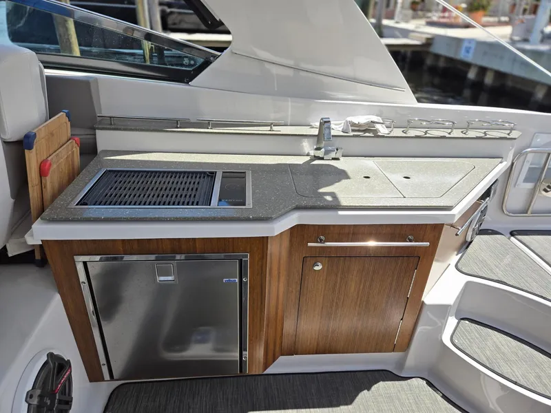 Slide: The Image of 2019 Four Winns H350 boat kitchenette with sink, grill, and storage cabinets. - 8