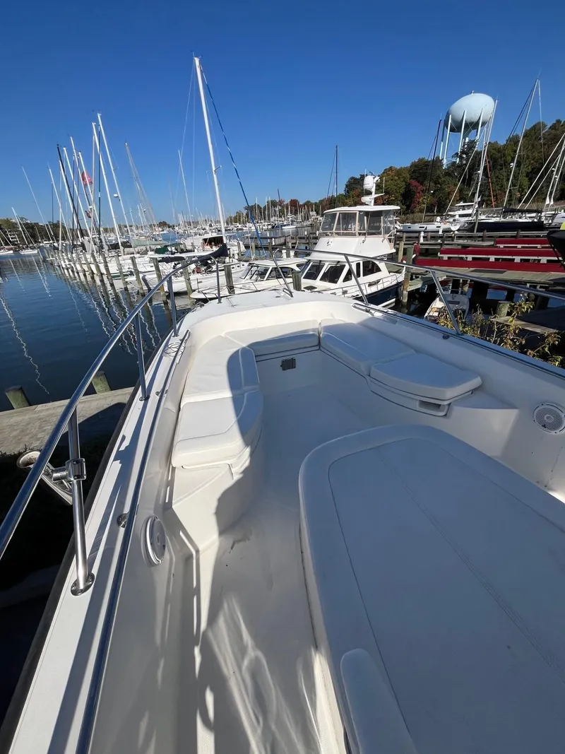 Slide: The Image of 2014 Boston Whaler 270 Dauntless boat docked at marina, clear sky, sailboats in background. - 10