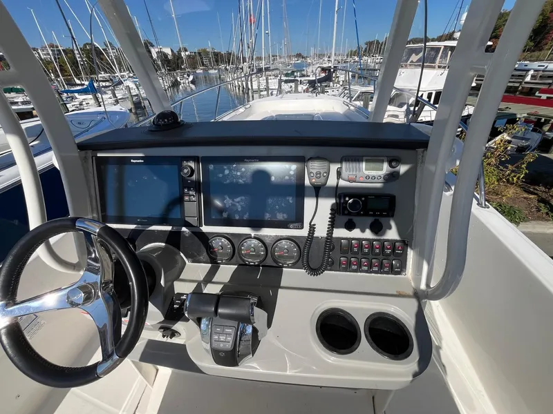Slide: The Image of 2014 Boston Whaler 270 Dauntless helm with navigation controls and marina view. - 18