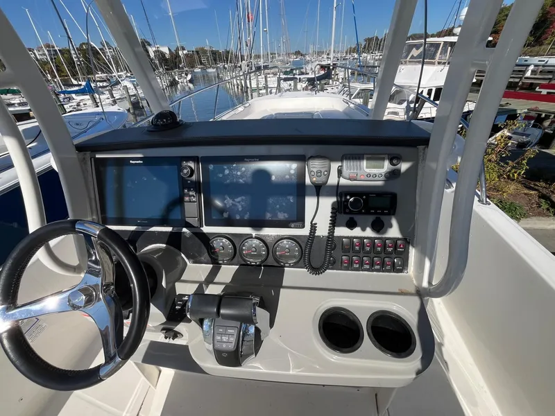 Slide: The Image of 2014 Boston Whaler 270 Dauntless helm with navigation controls and marina view. - 19