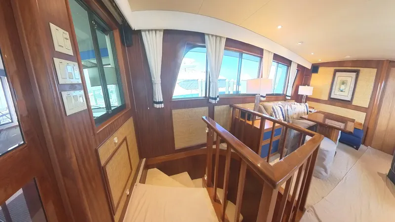 Slide: The Image of Interior of 1982 Hatteras 65 LRC yacht, featuring wood paneling and large windows. - 19