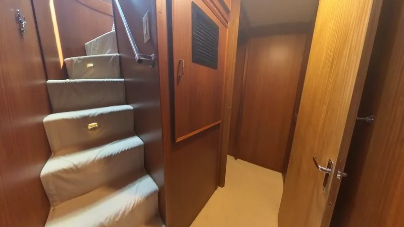 Slide: The Image of Interior hallway of 1982 Hatteras 65 LRC yacht with carpeted stairs and wooden paneling. - 20