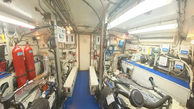 Slide: The Image of Engine room of 1982 Hatteras 65 LRC yacht, featuring equipment and fire extinguishers. - 35