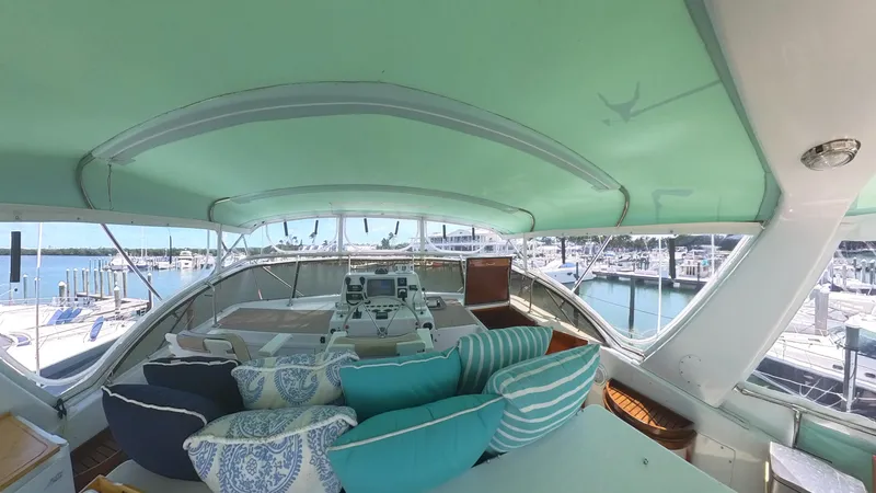 Slide: The Image of 1982 Hatteras 65 LRC yacht interior with teal canopy and patterned cushions at marina. - 41