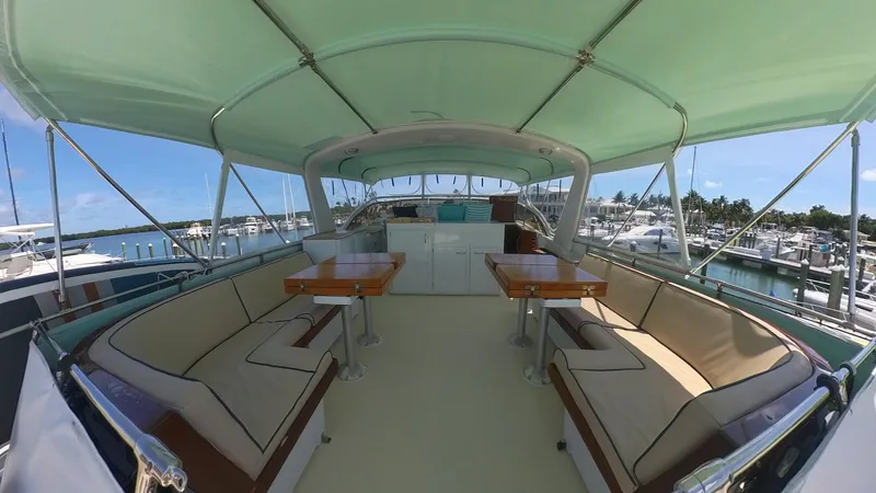 Slide: The Image of 1982 Hatteras 65 LRC yacht deck with seating and tables, docked at marina. - 43