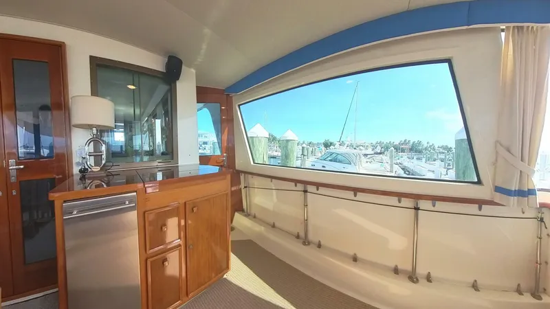 Slide: The Image of Interior view of 1982 Hatteras 65 LRC yacht with large window and wooden cabinetry. - 7