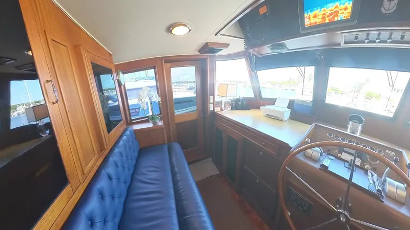 Slide: The Image of Interior of 1982 Hatteras 65 LRC yacht with blue seating and wooden helm. - 8