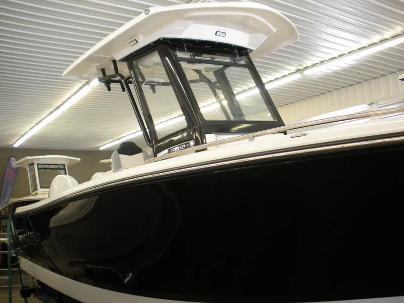 Slide: The Image of 2025 Robalo R250 Center Console boat in showroom, featuring sleek black and white design. - 2