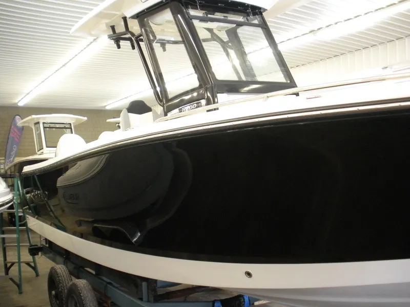 Slide: The Image of 2025 Robalo R250 Center Console boat in showroom, black hull, sleek design. - 3