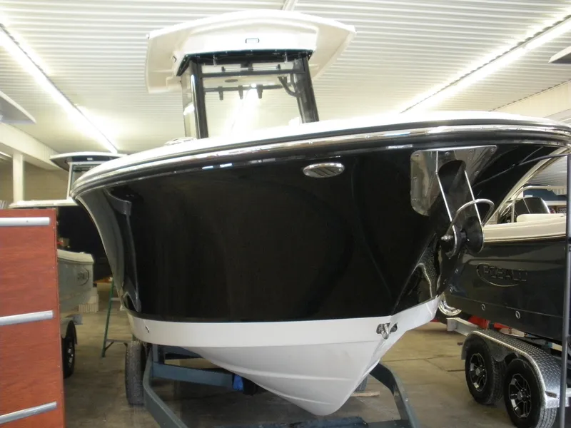 Slide: The Image of 2025 Robalo R250 Center Console boat in showroom, black hull, on trailer. - 4