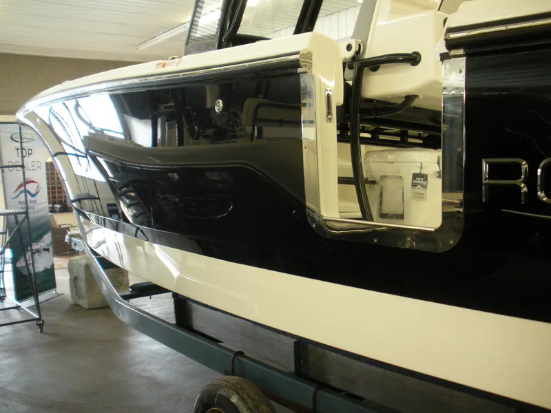 Slide: The Image of 2025 Robalo R250 Center Console boat, sleek black and white design, side view in showroom. - 5