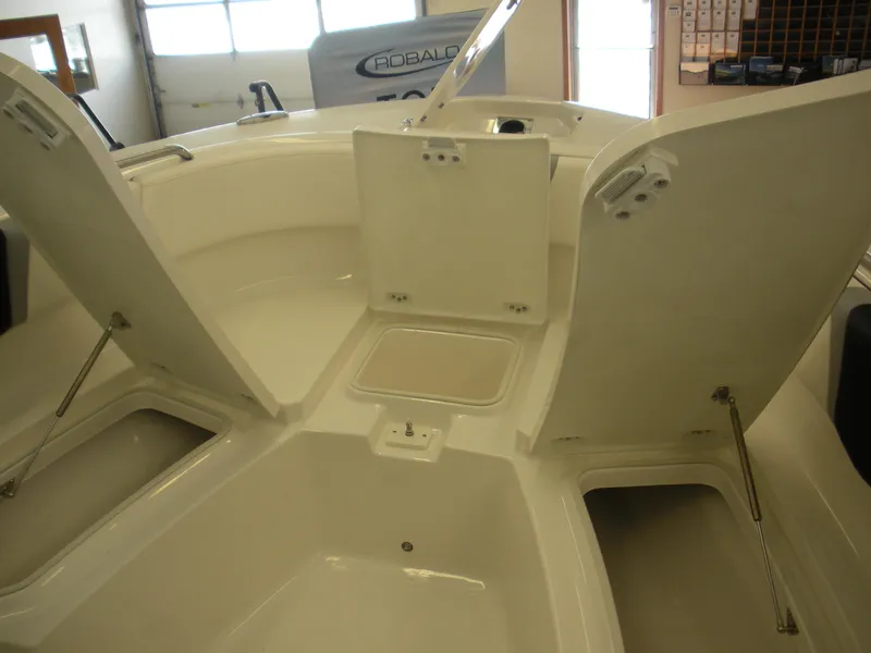 Slide: The Image of 2025 Robalo R250 Center Console boat storage compartments open in showroom. - 7