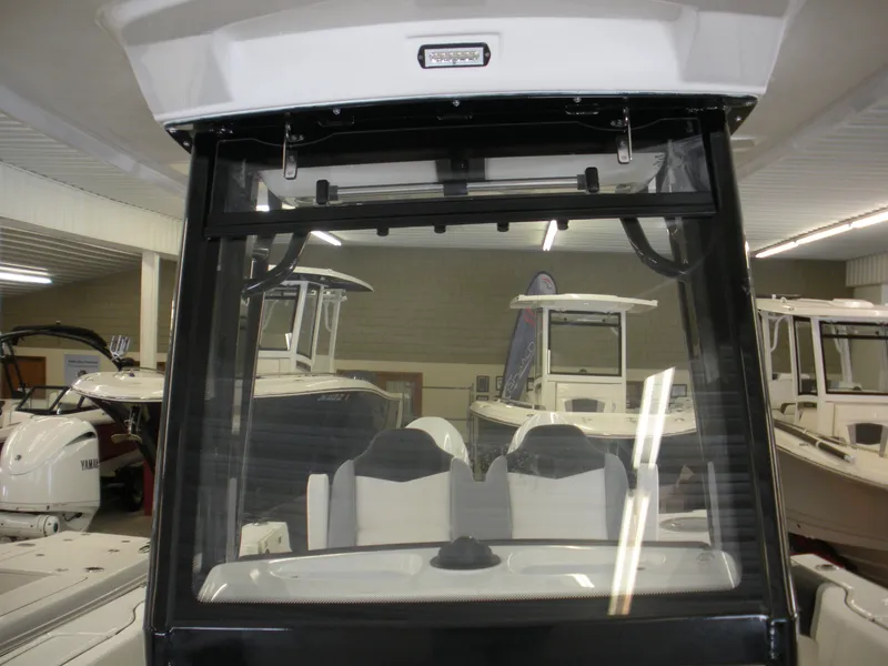 Slide: The Image of 2025 Robalo R250 Center Console boat interior with seating and windshield in showroom. - 8