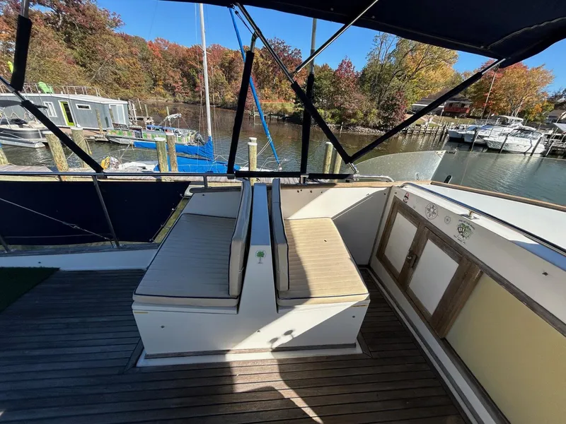 Slide: The Image of 1986 Grand Banks 42 Classic yacht deck with seating, docked by autumn trees. - 12