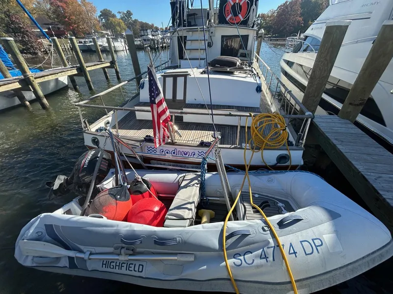 Slide: The Image of 1986 Grand Banks 42 Classic yacht docked with inflatable dinghy, American flag displayed. - 3