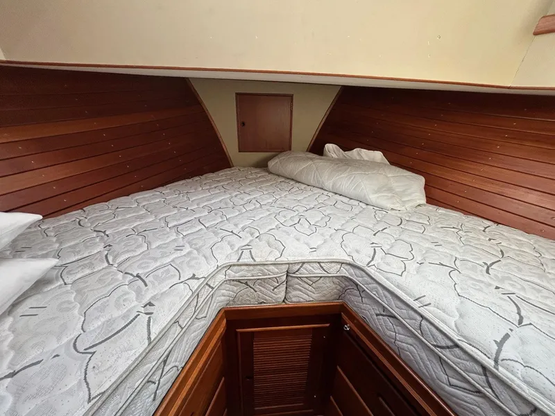 Slide: The Image of 1986 Grand Banks 42 Classic cabin with wooden paneling and comfortable bedding. - 44