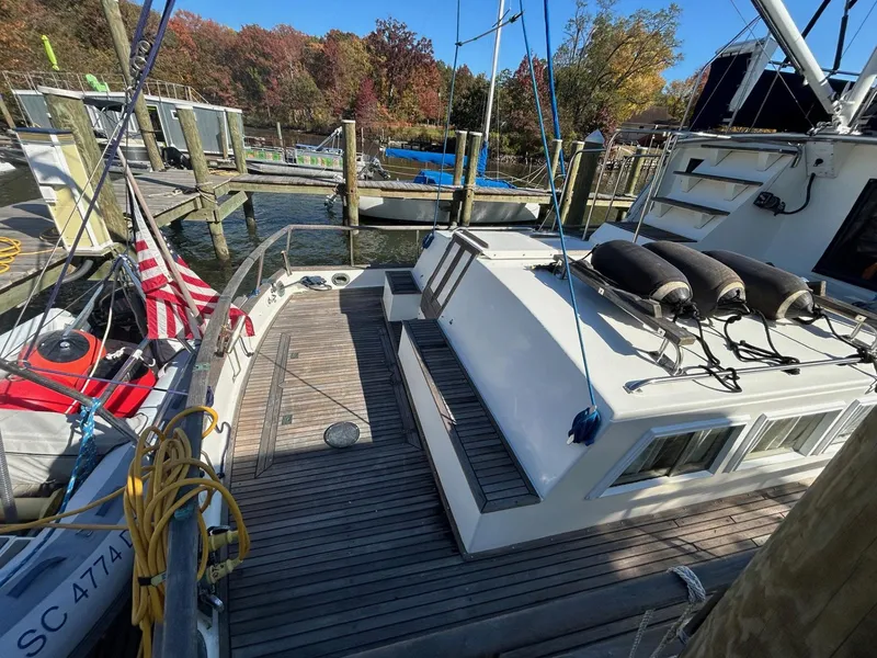 Slide: The Image of 1986 Grand Banks 42 Classic yacht docked, featuring spacious deck and American flag. - 5