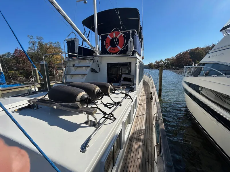 Slide: The Image of 1986 Grand Banks 42 Classic yacht docked, featuring deck and lifebuoy under clear blue sky. - 8
