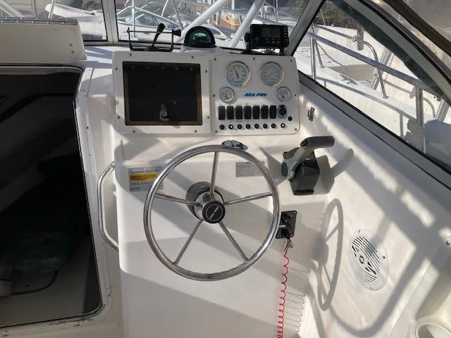 Slide: The Image of 2002 Sea Pro 235 Walk Around boat dashboard with steering wheel and gauges. - 11