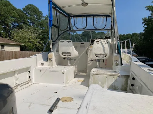 Slide: The Image of 2002 Sea Pro 235 Walk Around boat interior with seating and canopy, parked outdoors. - 6