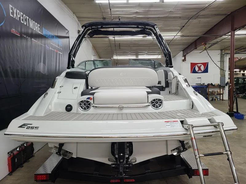 Slide: The Image of 2024 Crownline Eclipse E255 SURF boat in showroom, rear view with seating and speakers. - 2
