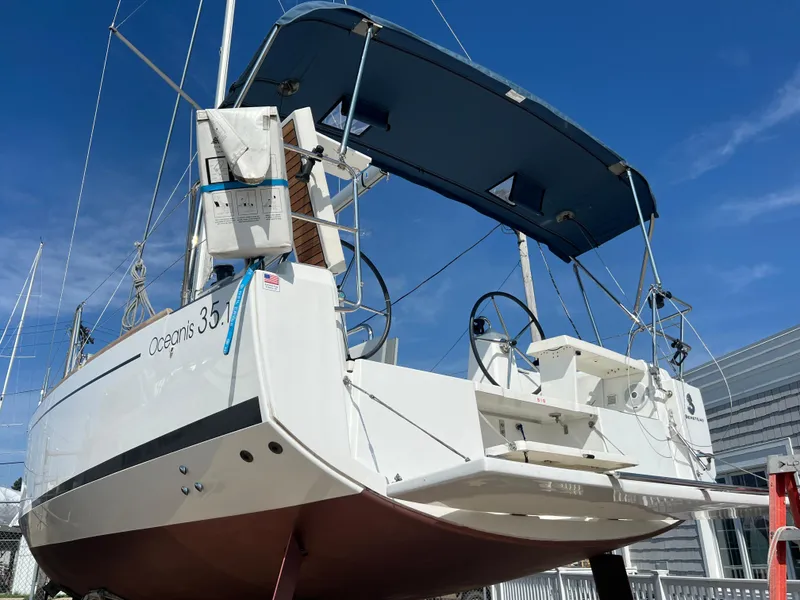 Slide: The Image of 2019 Beneteau Oceanis 35.1 sailboat with blue canopy, docked under clear sky. - 3