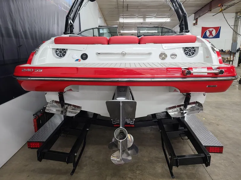 Slide: The Image of 2024 Crownline 240 SS SURF boat, red and white, rear view in a showroom. - 2