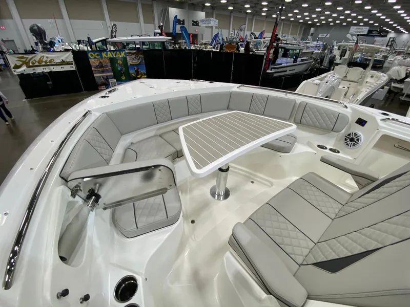 Slide: The Image of 2024 Pursuit S 358 boat interior with cushioned seating and table at a boat show. - 15
